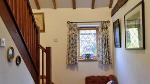 A staircase with wooden railings, a window with floral curtains, and a cushioned bench with pillows.