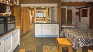 A compact kitchen with white cabinets, a central island, and a dining area with a bench and table.
