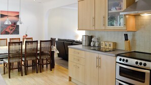 Une cuisine moderne avec des meubles en bois, une cuisinière et un coin repas comprenant des chaises et une table.