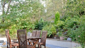 Une terrasse avec des meubles en bois et un chemin de gravier.