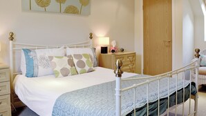 Une chambre à coucher avec un lit, une table de chevet, une lampe et une porte.