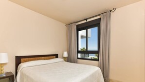 Een hotelkamer met een bed, nachtkastjes, een raam met gordijnen en uitzicht.
