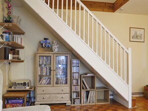 A staircase with white railings leading to a landing. Below, there are wooden bookshelves filled with books and decorative items.