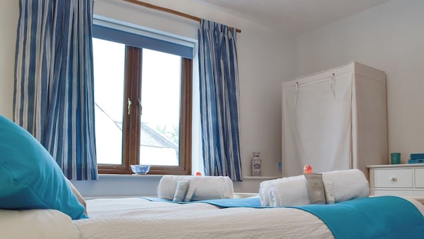 A bedroom with two beds, a wardrobe, a window with curtains, and a bedside table with a lamp. - 2 bedroom accommodation in Abergavenny (Abergavenny)
