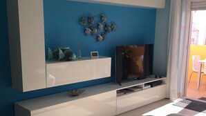 A modern living room with a blue accent wall, a white entertainment unit, and a patterned floor.