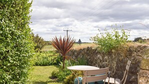 Un jardín con una mesa y sillas, un muro de piedra y una variedad de plantas.