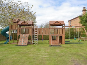 A wooden play structure with a slide, climbing net, and swings. - Eldin Hall Cottage 1 - UK2483 (Scarborough)