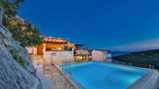 A poolside view of a coastal property with a stone wall, a swimming pool, and a building with multiple balconies overlooking the sea. - Awesome home in Vinisce (Vinisce)
