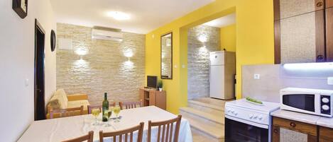 A compact kitchen with a dining area, a refrigerator, a microwave, and a stove.