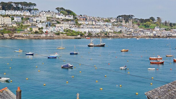 A coastal town with a harbor filled with boats, houses along the shore, and a clear sky. - A characterful holiday home with an attractive open plan layout. (Lerryn)