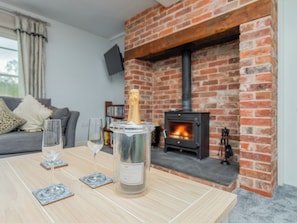 A cozy living room with a brick fireplace, a table with a bottle of champagne, and two glasses.
