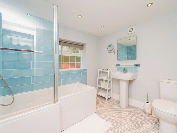 A bathroom with a bathtub, shower, sink, and toilet.