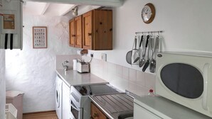 Una cucina compatta con mobili in legno, forno integrato, microonde e lavello.