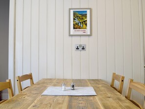 Una mesa de comedor de madera con un mantel individual, dos saleros y pimenteros, y un cuadro enmarcado de un puente en Derbyshire.