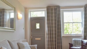 A cozy living room with a sofa, a coffee table, a chair, a door, and a window with curtains. - 2 bedroom accommodation in Wirksworth, near Matlock (Wirksworth, near Matlock)