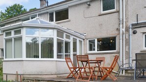 A house with a conservatory, a patio with a table and chairs, and a garden area. - 4 bedroom accommodation in Keswick (Keswick)