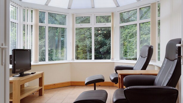 A conservatory with large windows, a television, and seating. - 4 bedroom accommodation in Keswick (Keswick)