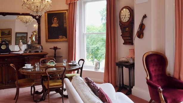 Ein formeller Salon mit Esstisch, Stühlen, einer Couch, einer Chandelier, einer Uhr und einer Violine.