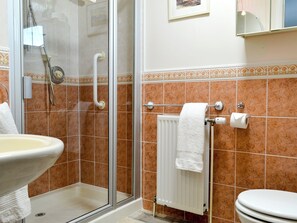 A bathroom with a glass shower enclosure, a white sink, a toilet, and a towel rack.