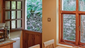 A cozy kitchen with wooden furniture, a stone wall, and a window with a view of greenery. - 3 bedroom accommodation in Beech Hill, near Bowness-on-Windermere (Beech Hill, near Bowness-on-Windermere)