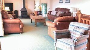 A cozy living room with leather sofas, a wooden coffee table, and a fireplace. - 4 bedroom accommodation in Fairy Cross, Bideford (Fairy Cross, Bideford)