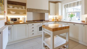 A kitchen with white cabinets, a wooden countertop, a built-in oven, and a window with flowers. - 1 bedroom accommodation in Gargrave, near Skipton (Gargrave, near Skipton)