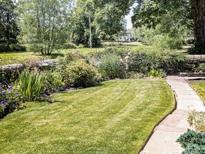 A well-maintained garden with a stone pathway, lush greenery, and a bench. - 1 bedroom accommodation in Gargrave, near Skipton (Gargrave, near Skipton)