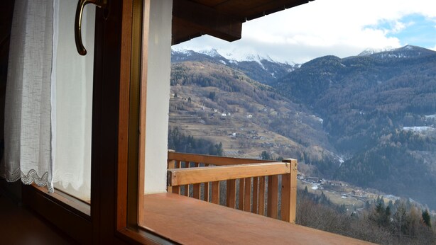 Un balcón de madera con vistas a un paisaje montañoso.