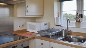 Une cuisine équipée d’un four à micro-ondes, d’une cuisinière, d’un évier et d’un plan de travail en bois.