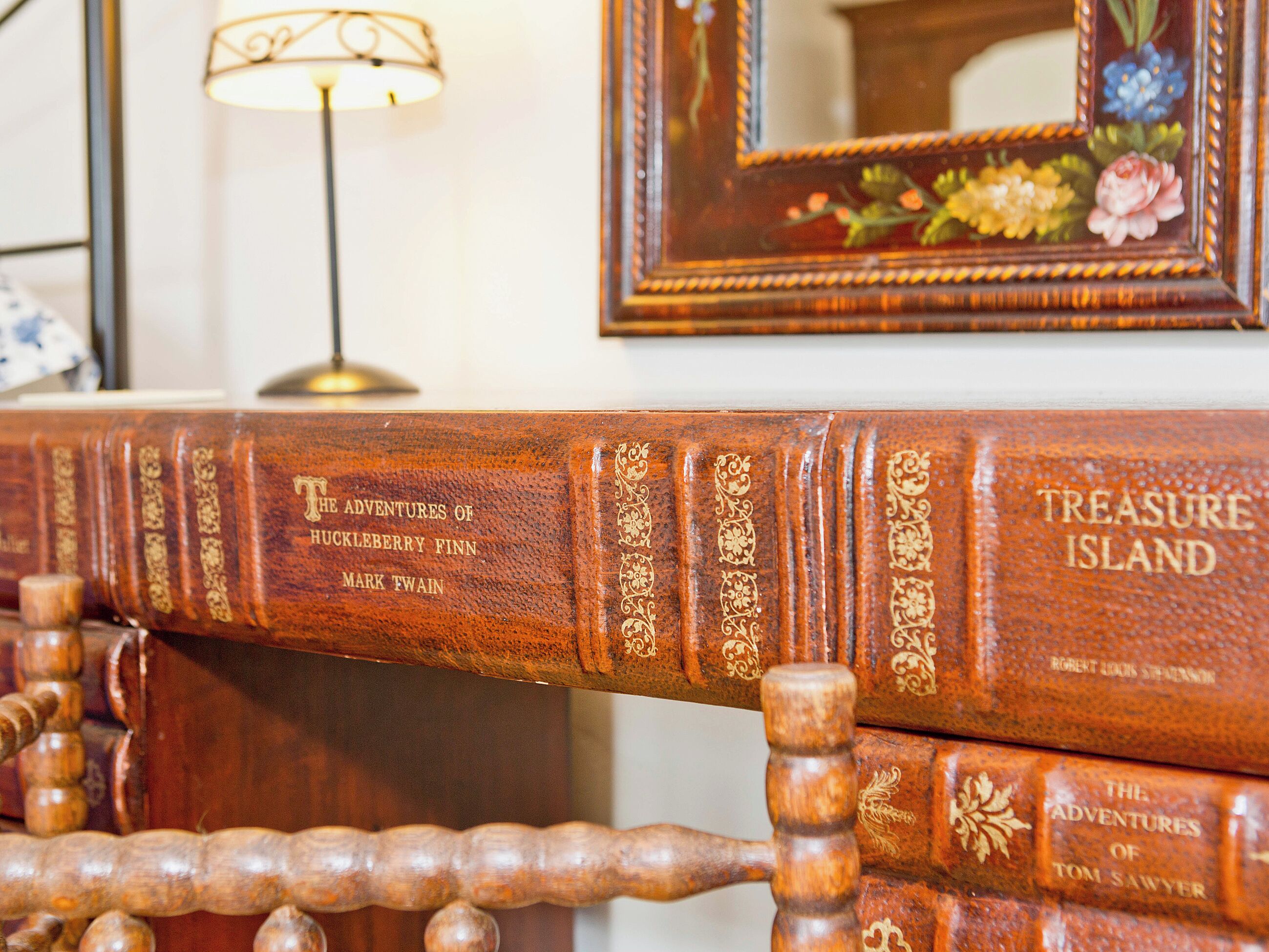 Uma estante de madeira com livros, incluindo 'A Ilha do Tesouro' de Robert Louis Stevenson.