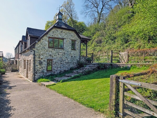 A stone building with a sloped roof, a small porch, and a wooden fence.