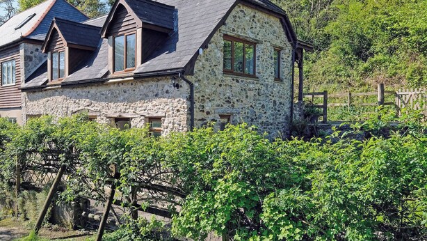 A stone house with a sloped roof, wooden windows, and a chimney. - Branscombe beach is only 1½ miles away and the Jurassic Coast is nearby. (Branscombe)