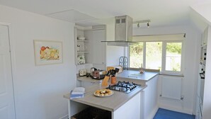 A modern kitchen with a gas stove, toaster, and various kitchen utensils. - Branscombe beach is only 1½ miles away and the Jurassic Coast is nearby. (Branscombe)