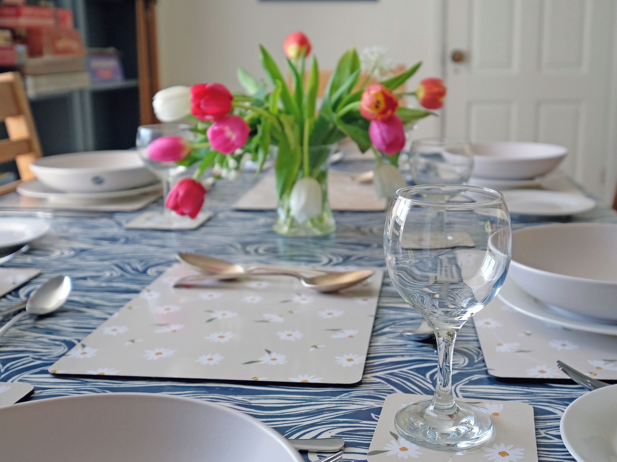 A dining table with a vase of tulips, a glass of water, and various dishes and cutlery.