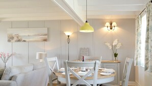Un coin repas avec une table ronde, des chaises blanches et une suspension jaune.