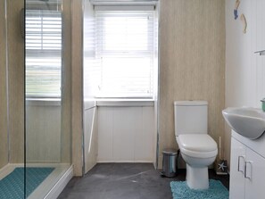 A bathroom with a toilet, a sink, a shower, and a window. - 2 bedroom accommodation in Rhoscolyn, near Holyhead (Rhoscolyn, near Holyhead)