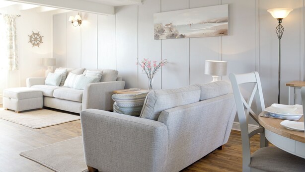 Un salon moderne avec un canapé gris, une table ronde en bois et une chaise blanche.