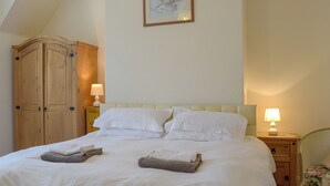 Una cama bien hecha con sábanas blancas y dos toallas dobladas al pie.