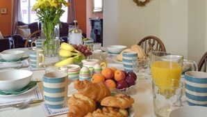 Una mesa de desayuno con croissants, frutas y un vaso de jugo de naranja.