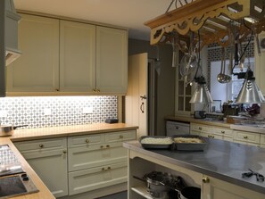 A kitchen with light green cabinets, a tiled backsplash, and hanging utensils. - 8 bedroom accommodation in Colquite, Washaway (Colquite, Washaway)