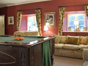 Une pièce avec une table de billard, un canapé et une fenêtre avec des rideaux.