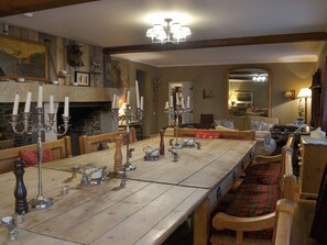 A dining room with a long wooden table, multiple candelabras, and a fireplace.
