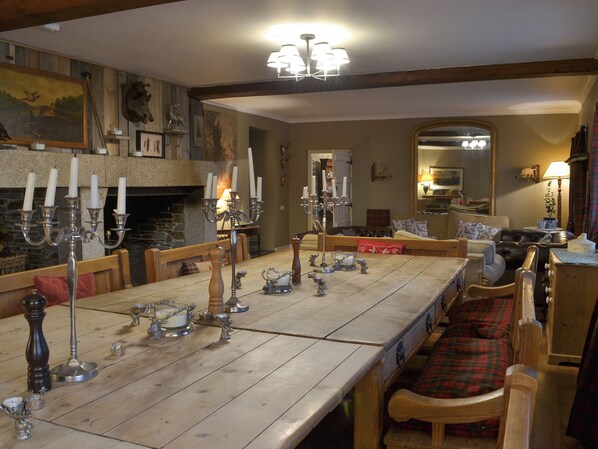 Comedor con una larga mesa de madera, múltiples candelabros y una chimenea.