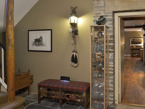 Un escalier avec une rampe en bois, un banc avec un coussin à carreaux, un tableau encadré, un luminaire fixé au mur et une vitrine contenant des bijoux.