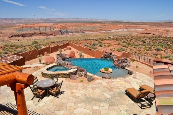 Zona de piscina con jacuzzi, sillas de descanso y vistas al paisaje desértico.