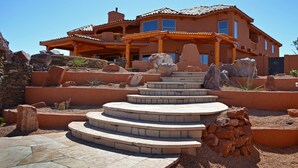 A multi-story house with a patio area, stone steps, and rock landscaping.