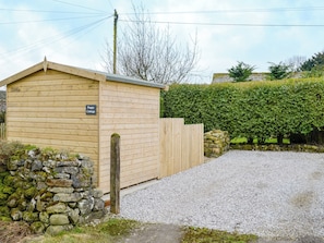 A wooden cottage with a stone wall and a gravel driveway.