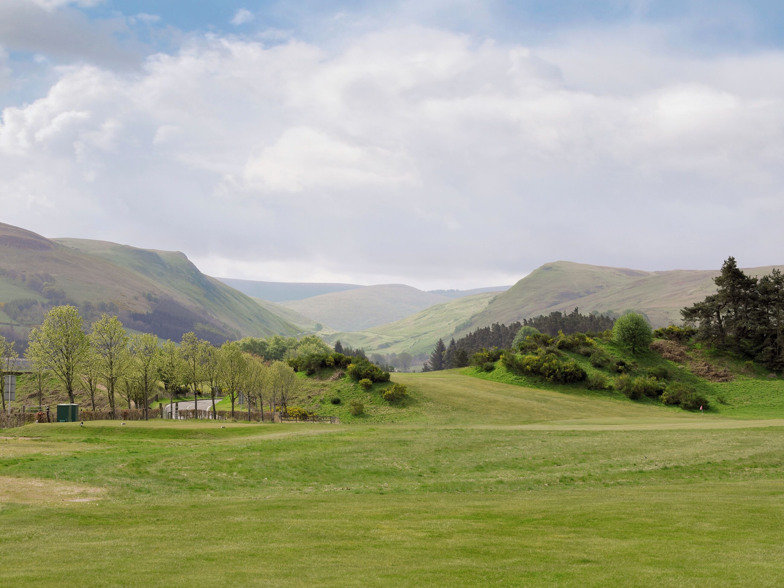A wide, open field with rolling hills in the background.