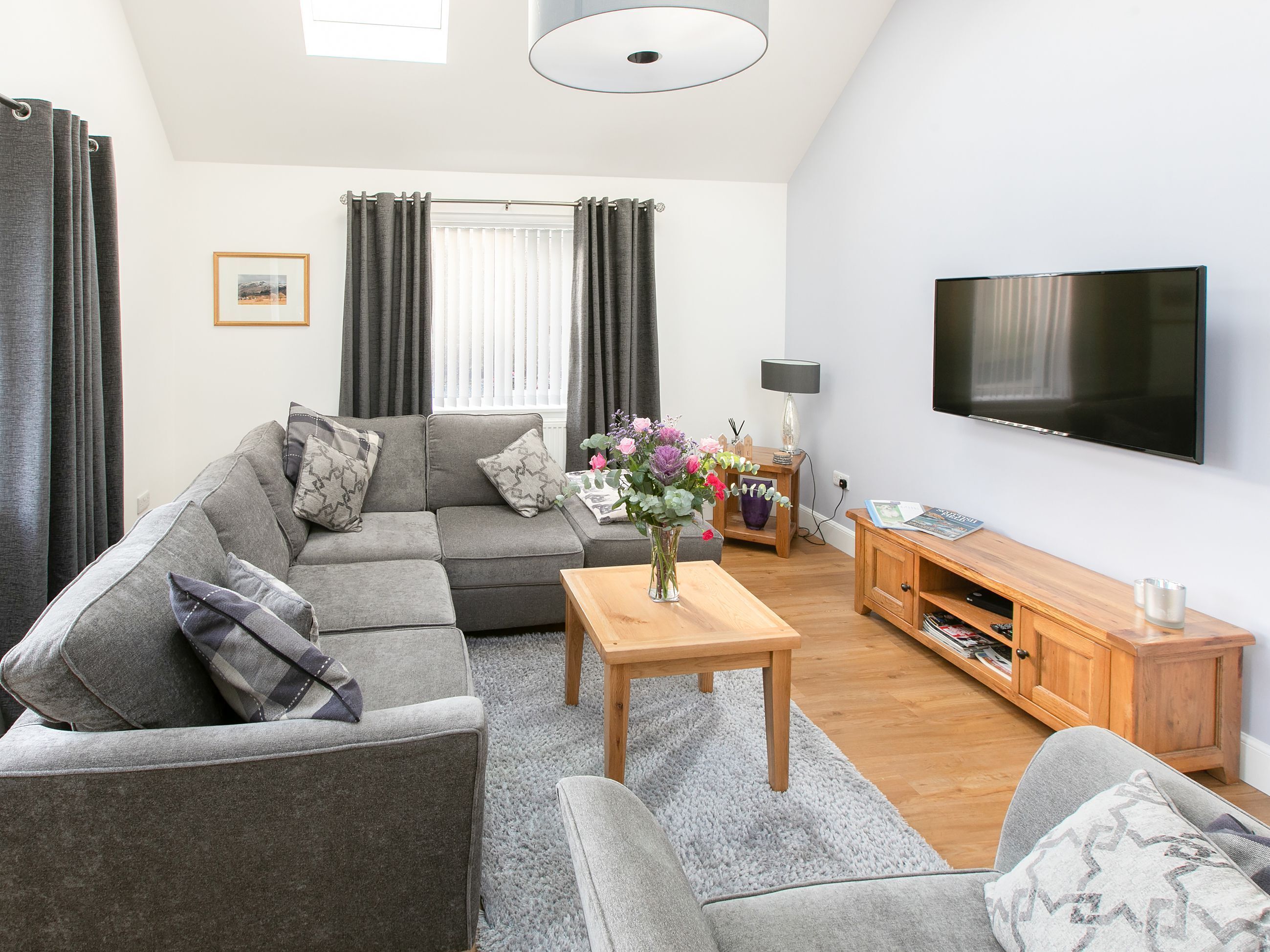 A modern living room with a sectional sofa, a coffee table, and a flat-screen TV.