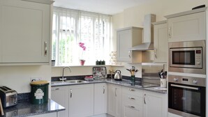 Una cucina moderna con mobili bianchi, un piano di lavoro in granito, elettrodomestici in acciaio inossidabile e una finestra vista verde.